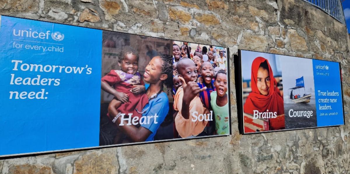 Eine Steinmauer, an der 2 Plakate von unicef hängen. Aufschrift 1. Plakat: Tomorrow's leaders need: Heart Soul. Aufschrift 2. Plakat: Tomorrows leaders create new leaders. Brains Courage.